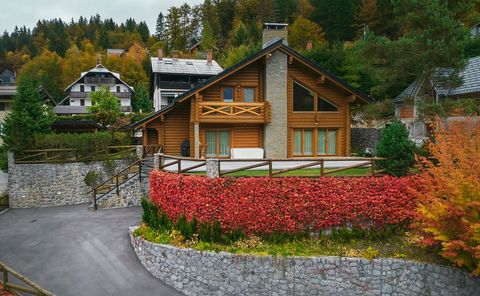 Aerial view of the chalet's front elevation, showing the gabled roof, tall glazing, a balcony, and the creeper-covered wall below.