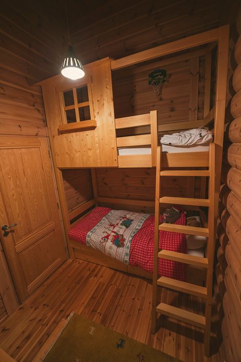 The children's room with a timber "hiška" house-frame bunk bed, a ladder, and red bedding.