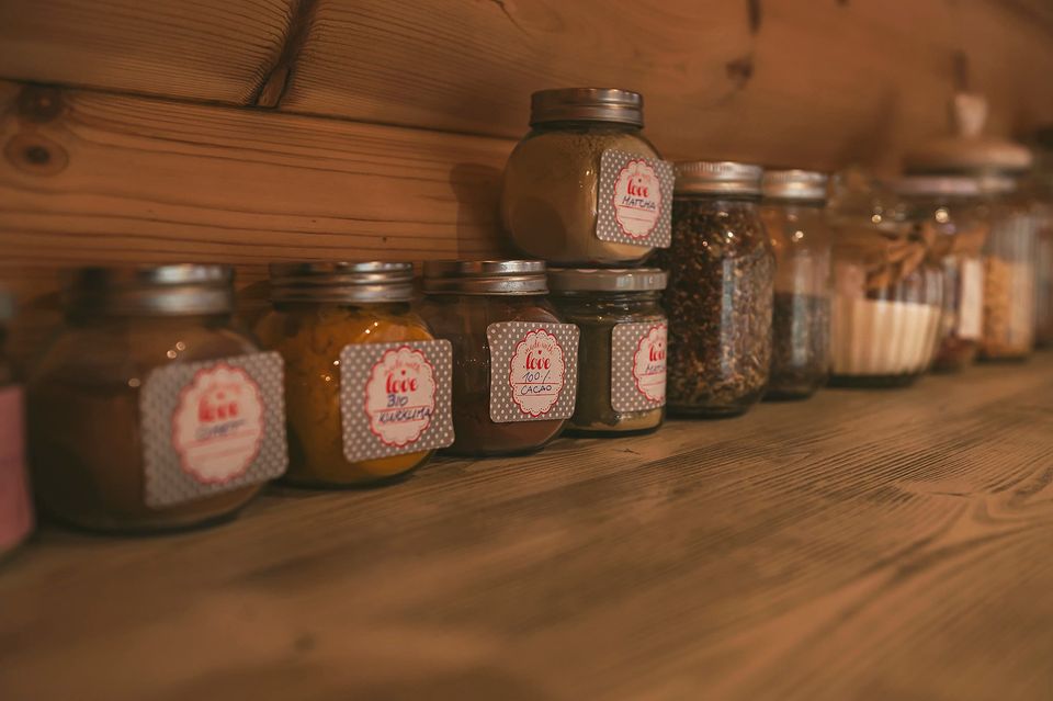 A row of labelled preserve jars on a timber shelf.
