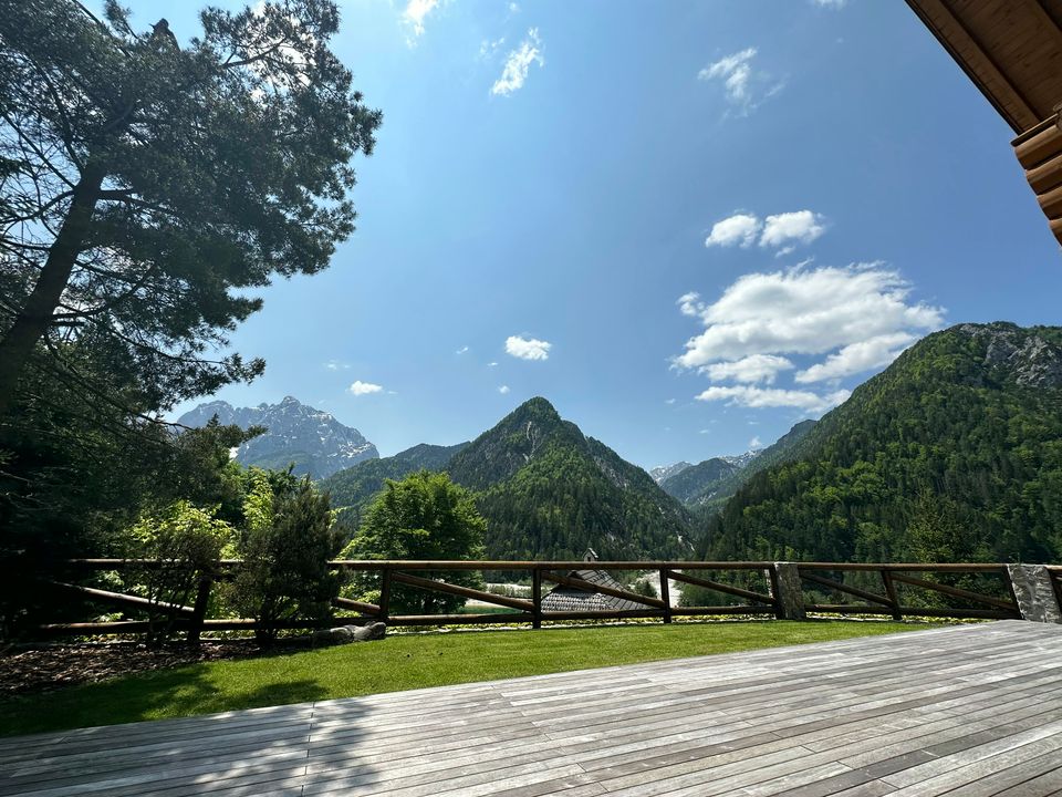 The timber sun deck and lawn in summer, with the mountains rising directly beyond the garden railing.